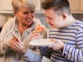 Mom and son with down syndrome standing in the kitchen smiling together